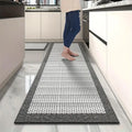 Tapis de cuisine long imitation tissée — antidérapant - Nesty, motif tressé noir et blanc dans une cuisine, avec une personne pieds nus dessus