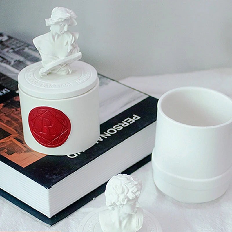 Photophore en plâtre sculpté Nesty - Photophore à buste féminin posé sur un livre, à côté du pot ouvert sans couvercle