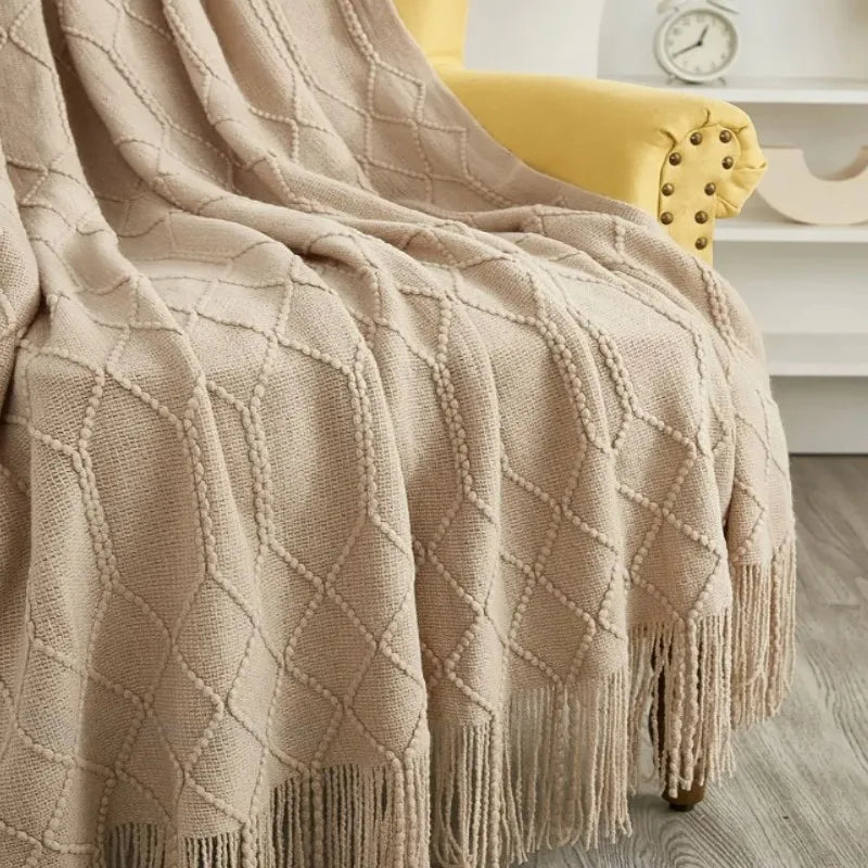 Plaid oversize tricoté Nesty - Coloris beige drapé sur fauteuil jaune, gros plan sur le motif tricoté et les franges