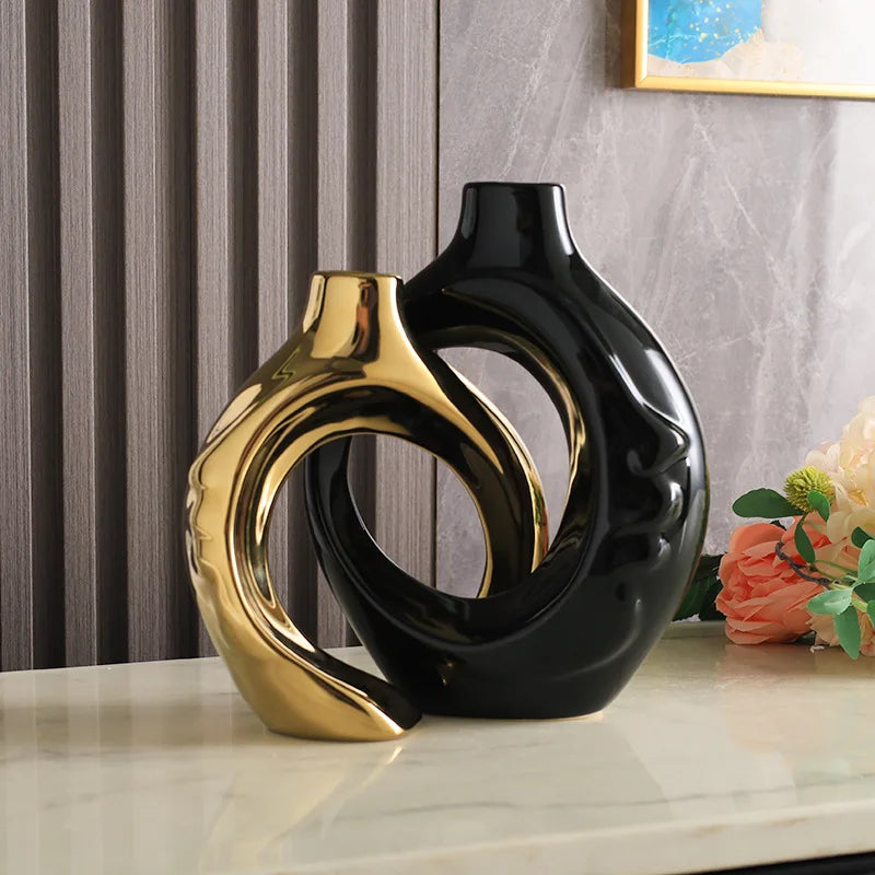 Vase en poterie Nesty - Coloris doré et noir entrelacés, près d'un cadre et de fleurs oranges