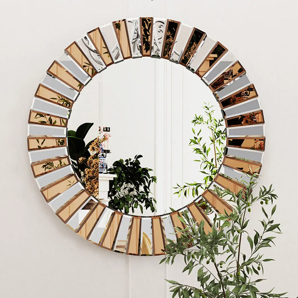 Grand miroir rond soleil à segments biseautés dorés et argentés, sur mur blanc avec plantes vertes - Nesty