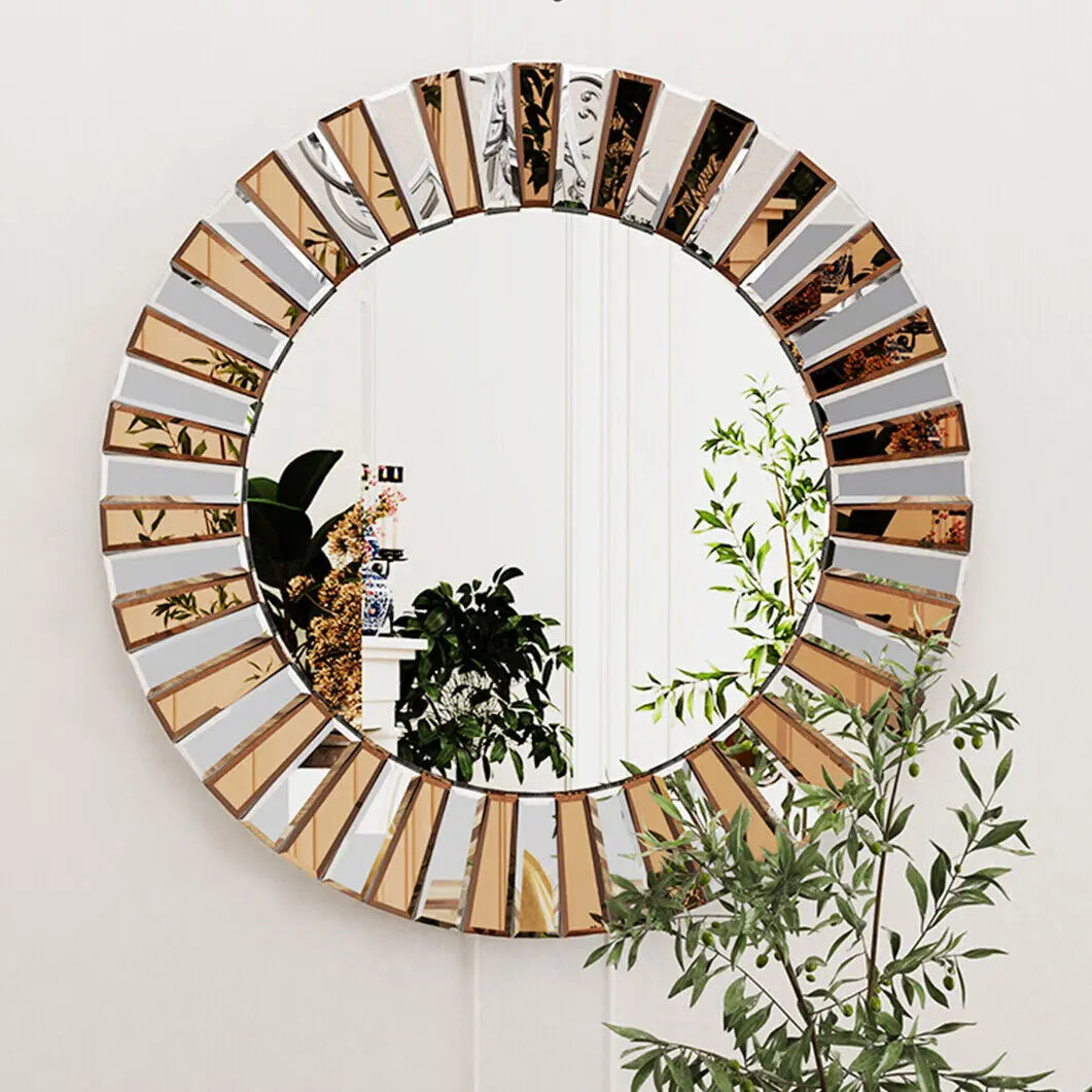 Grand miroir rond soleil à segments biseautés dorés et argentés, sur mur blanc avec plantes vertes - Nesty