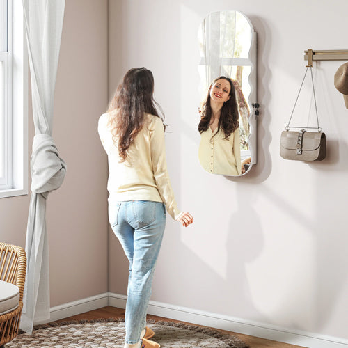 Armoire à bijoux miroir ondulée Nesty - Fixée au mur, reflet d'une femme se regardant dans le miroir