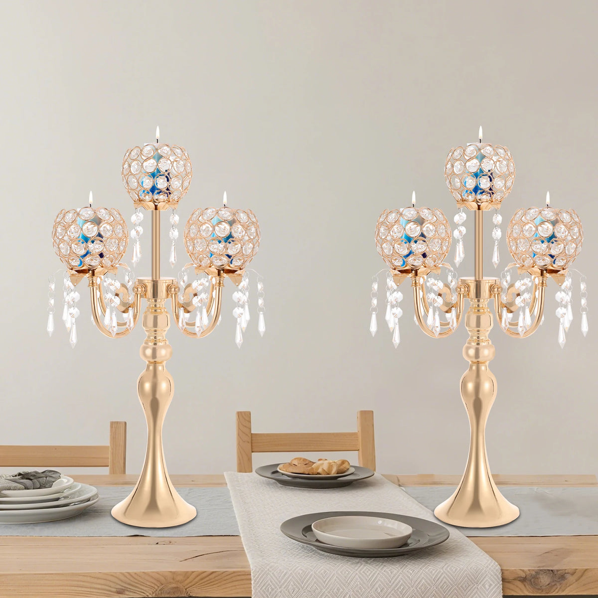 Bougeoir en verre Nesty - Deux candélabres dorés identiques sur une table en bois dressée avec assiettes grises, lot de 2 pièces
