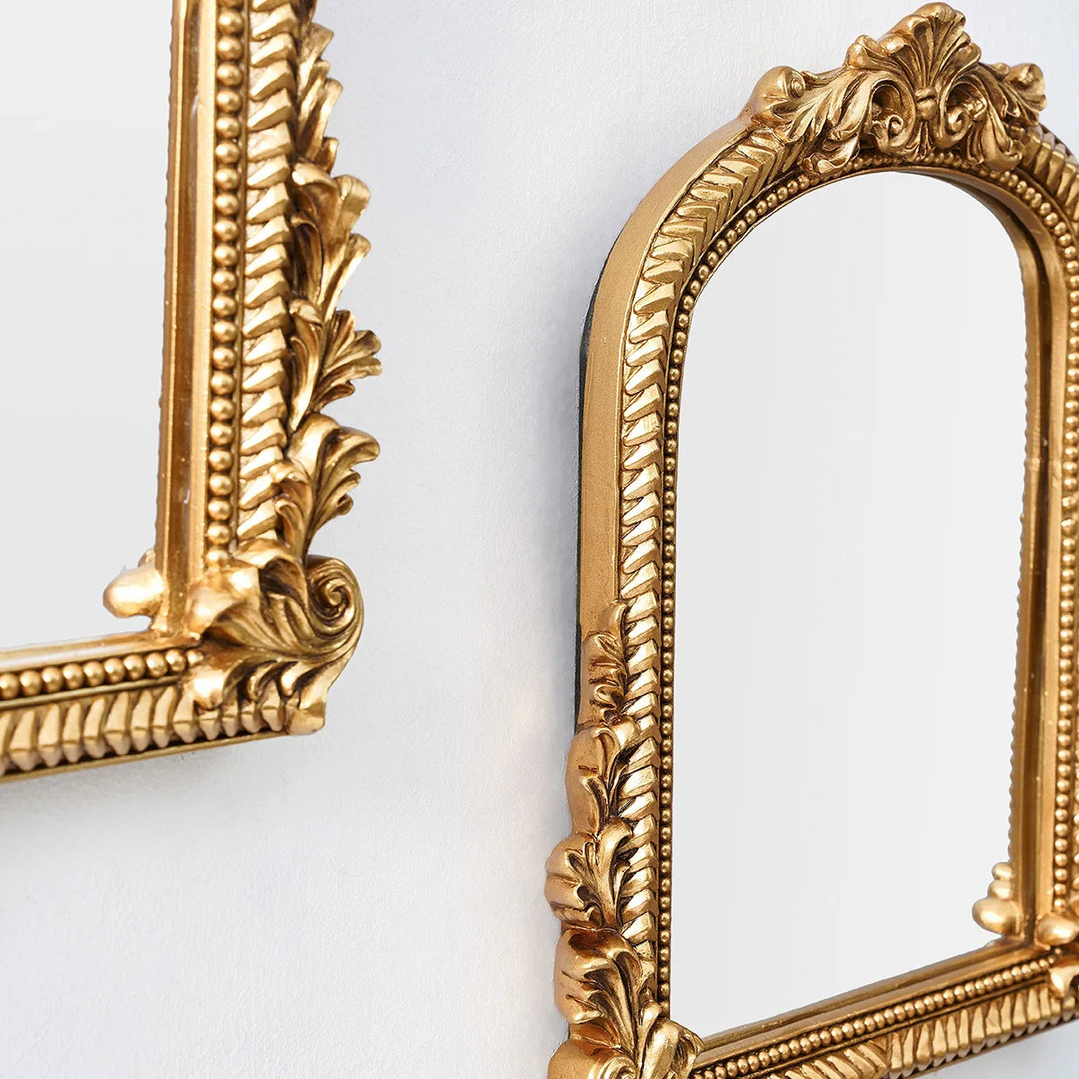 Miroir cintré doré ouvragé Nesty - Coiffeuse ou mur, gros plan sur les coins ouvragés du cadre doré de deux miroirs