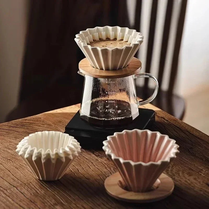Set dripper à café en céramique avec pichet en verre Nesty, montage avec dripper blanc et rose sur socle en bois, à côté du pichet complet sur table en bois