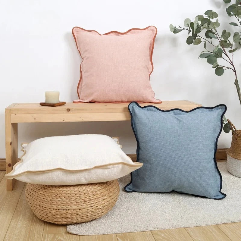 Housse de coussin en lin uni, bord ondulé, esprit bohème Nesty, quatre housses de coussin unies à bord ondulé liseré (rose corail, bleu ardoise, écru doré, blanc cassé), sur banc en bois, panier en osier et coussin bohème