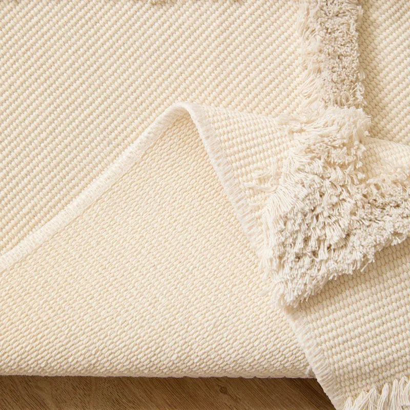 Tapis noué main à franges — motif ethnique - Nesty, gros plan sur un coin plié du tapis montrant la texture et les franges