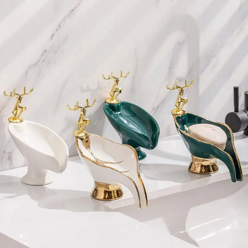 Quatre porte-savons en céramique forme feuille dorée avec figurine de cerf, coloris blanc et vert, alignés sur un plan en marbre - Nesty