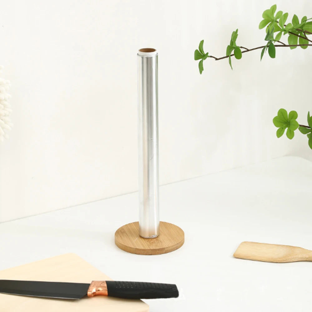 Porte-rouleau essuie-tout en bambou, vertical et rotatif Nesty, gros plan sur un rouleau de papier aluminium posé sur le socle en bambou, couteau et spatule en bois à proximité
