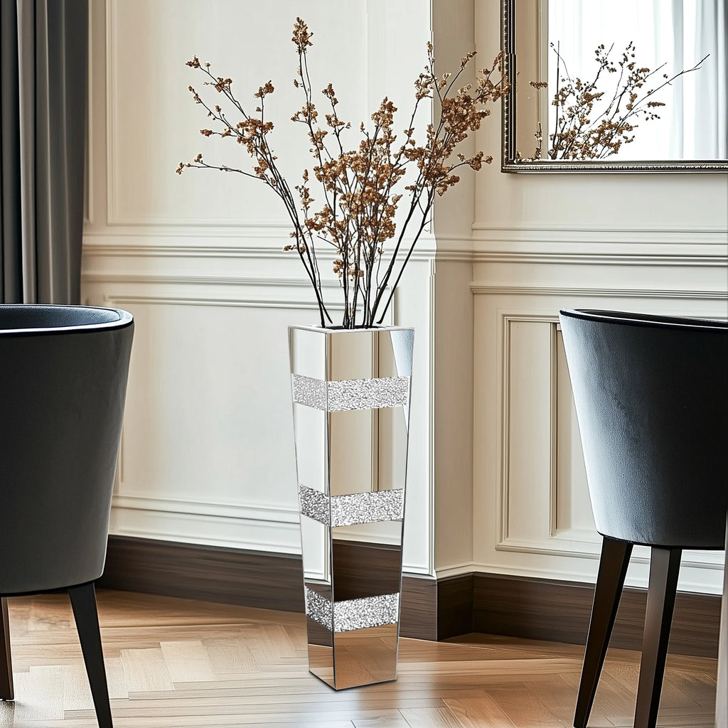 Vase sol en verre facetté, finition miroir - Nesty - Vase haut à bandes strassées garni de branches séchées dorées, entre deux fauteuils capitonnés bleu marine près d'un miroir