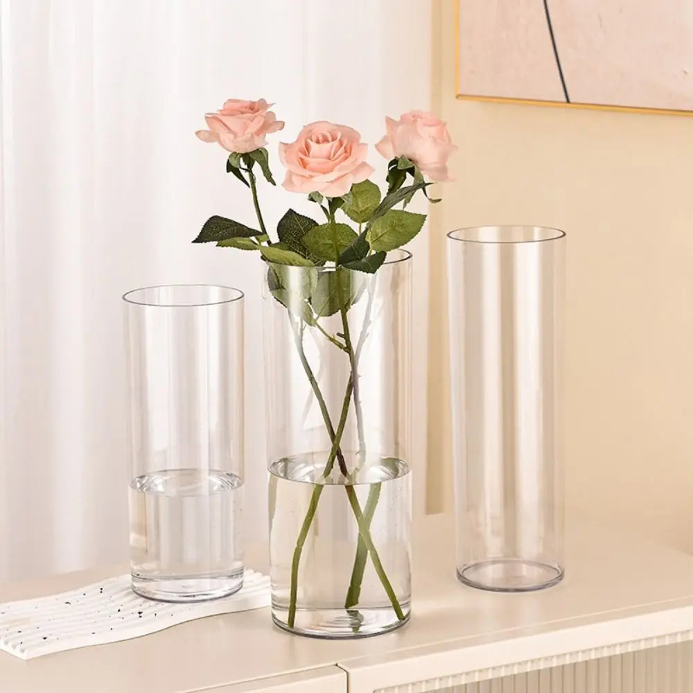 Vase cylindre en acrylique incassable Nesty - Trois tailles dont une avec roses roses, sur console beige devant un rideau