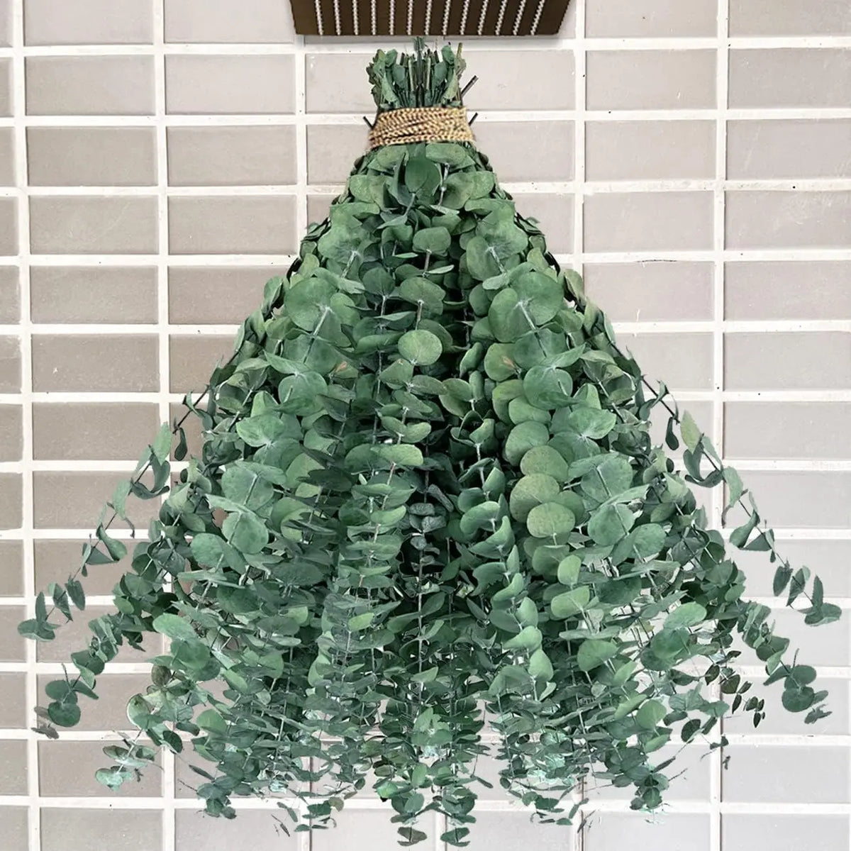 Bouquet suspendu de branches d'eucalyptus séché naturel 43 cm, attache en raphia, contre un mur carrelé beige - Nesty