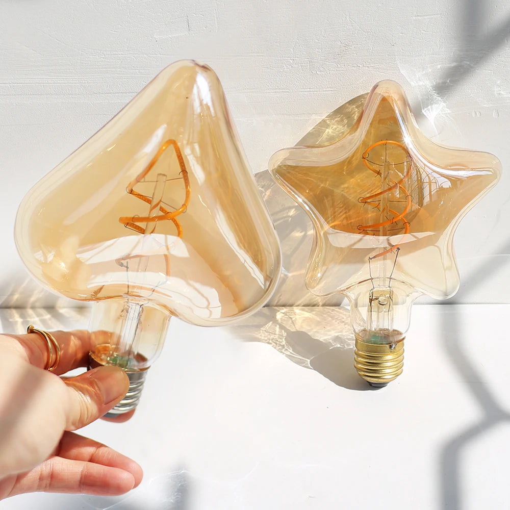 Ampoule LED Edison vintage Nesty - Formes cœur et étoile tenues en main au soleil