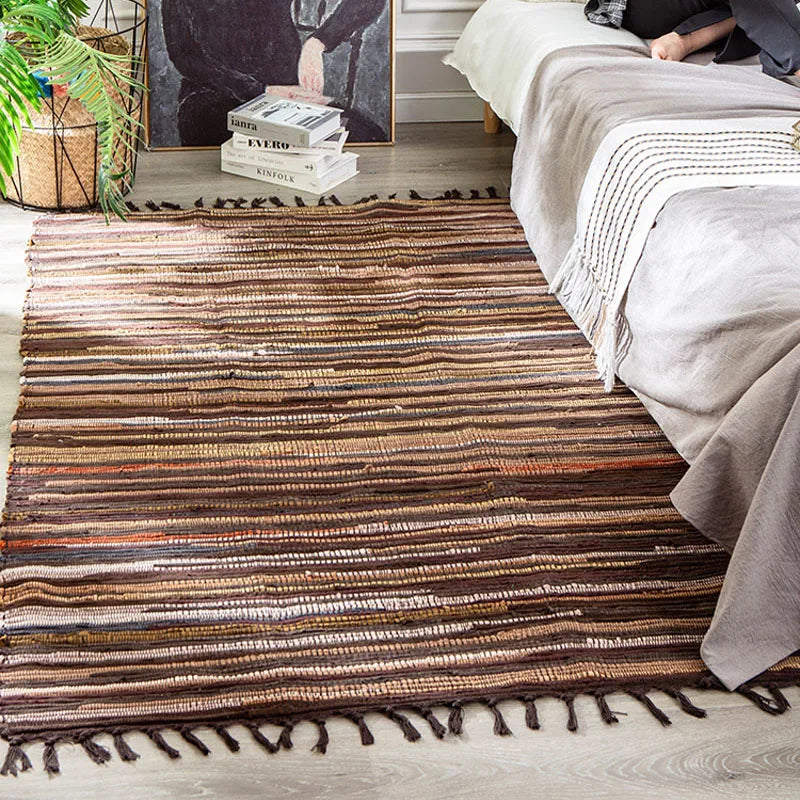 Tapis à franges tissé main — motif rayé - Nesty, tapis chiffon à rayures multicolores brun, orange et écru avec franges, posé au pied d'un lit
