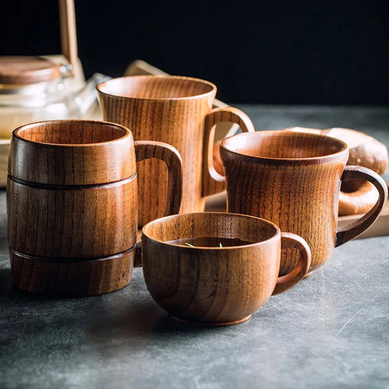 Tasse en bois avec anse, modèle artisanal Nesty, quatre tasses en bois de tailles différentes dont une remplie de thé, avec bocal et pain en fond