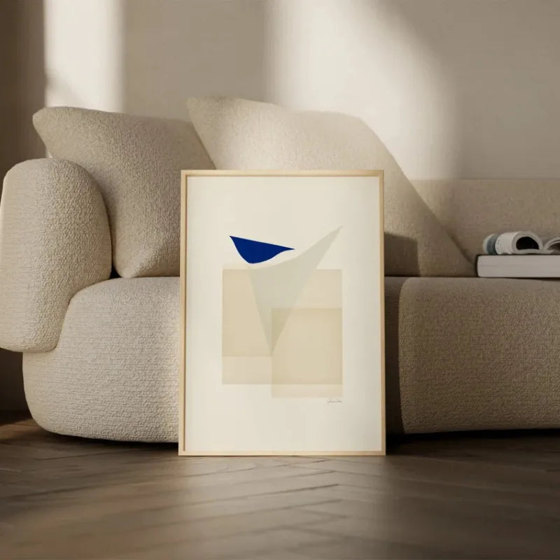 Toile imprimée géométrique texturée Nesty - Affiche encadrée d'un oiseau bleu stylisé sur formes beiges, posée contre un canapé