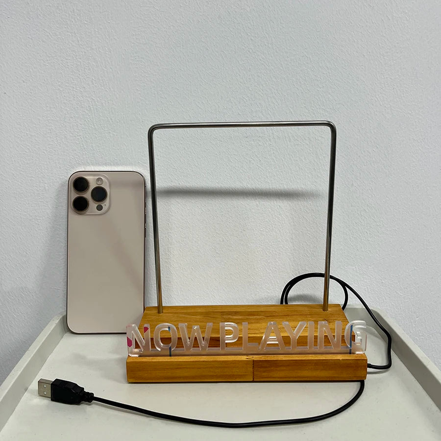 Support lumineux pour vinyle Nesty - Présentoir posé contre un mur à côté d'un smartphone, texte 'Now Playing' visible