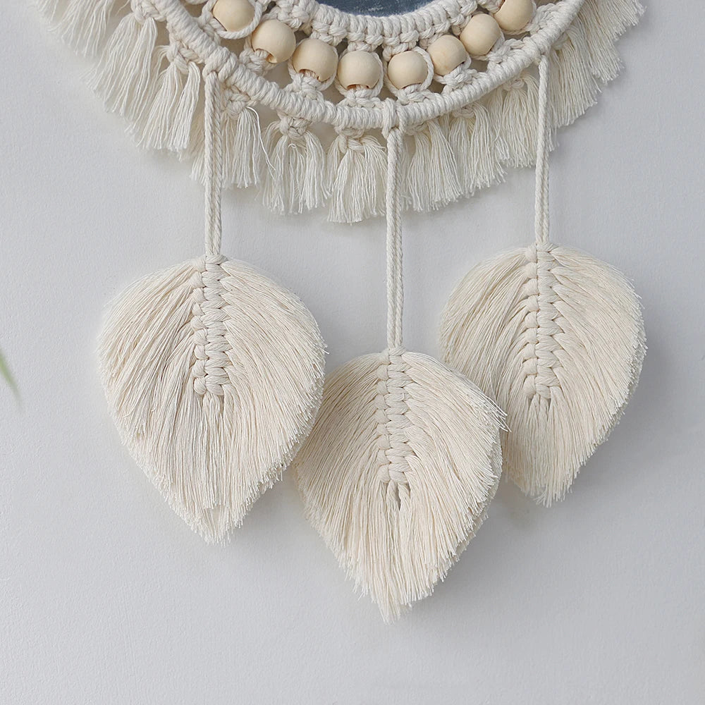 Trois plumes tressées en macramé suspendues sous le miroir à perles, gros plan sur le tissage - Nesty