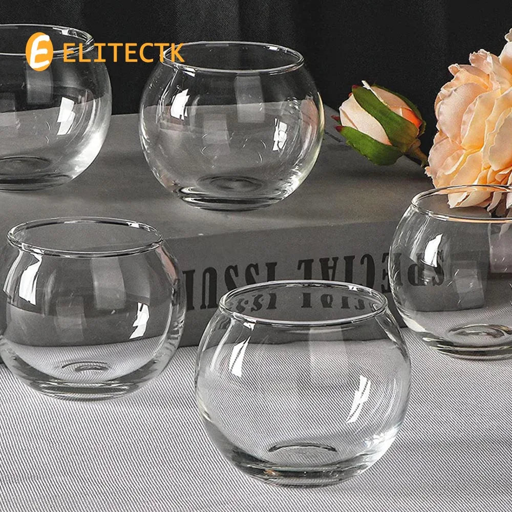 Photophore boule en verre transparent Nesty - Cinq exemplaires vides sur nappe grise avec roses