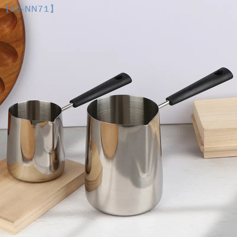 Casserole à manche long en inox pour lait et chocolat chaud Nesty, deux tailles inclinées, manches noirs, sur planche en bois
