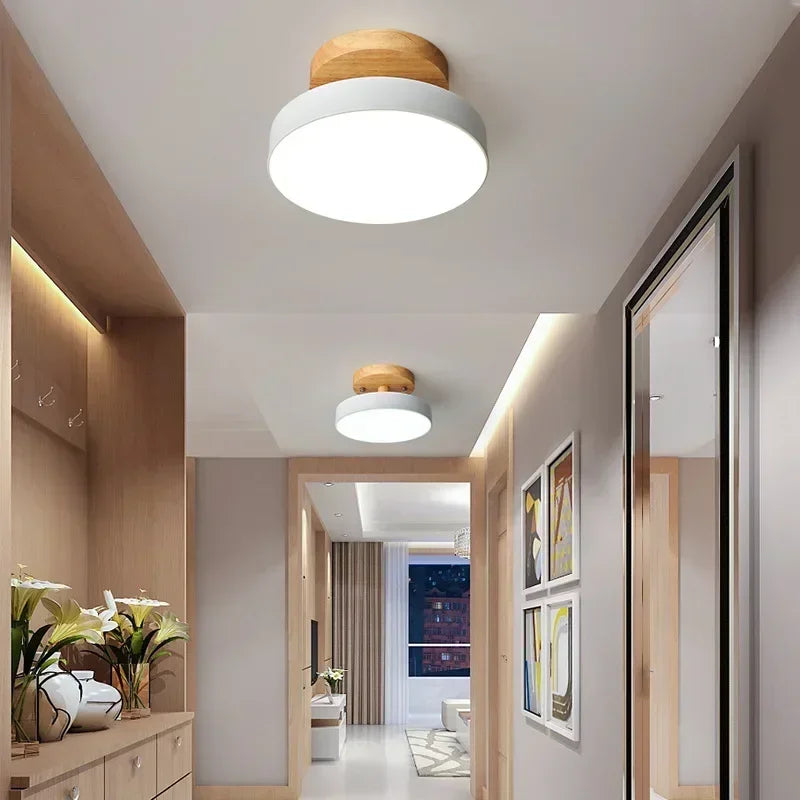 Plafonnier nordique en bois Nesty - Version blanche installée dans une entrée avec meuble en bois et fleurs