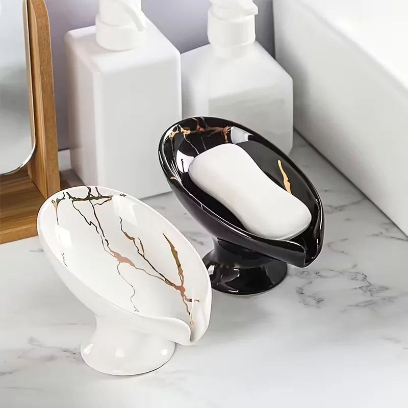 Duo de porte-savons en céramique effet marbre blanc et noir doré, sur un plan de salle de bain avec flacons blancs - Nesty