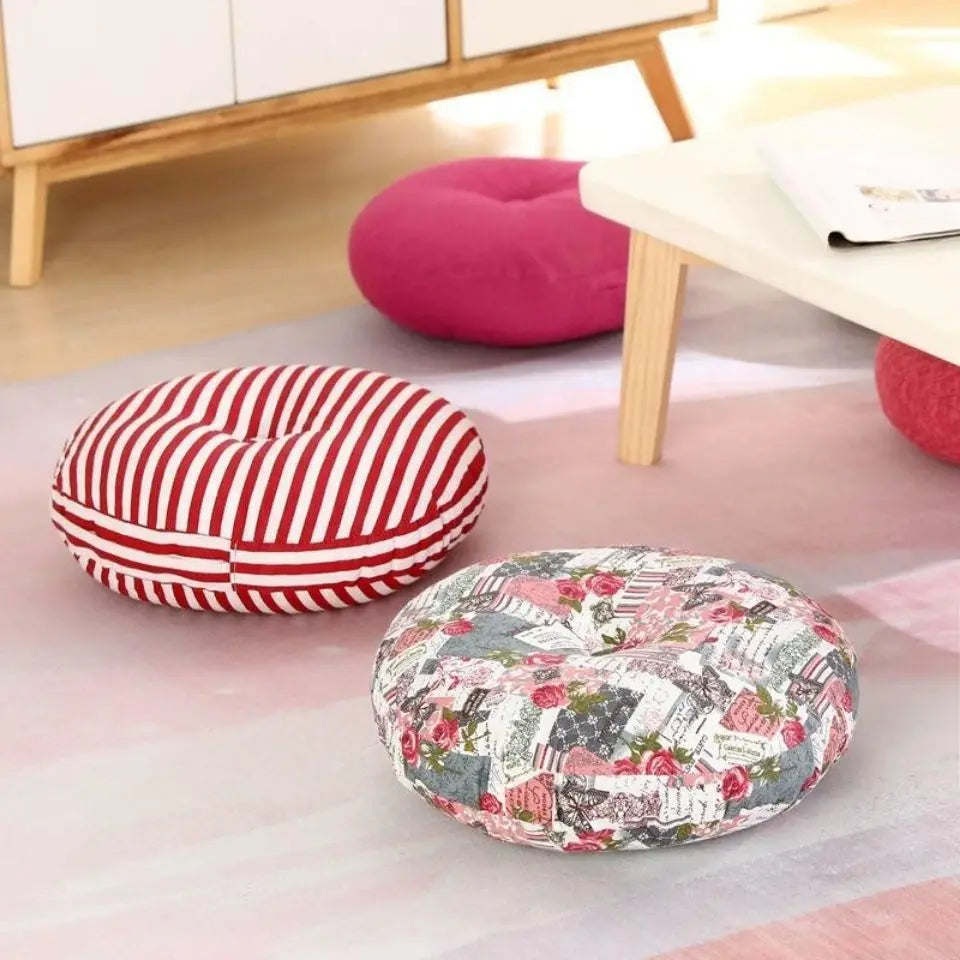 Grand coussin de méditation zafu en lin, pour banquette ou yoga Nesty, galette ronde à rayures rouges et blanches et galette à motif floral rose posées au sol près d'une table basse, galette rose fuchsia en fond