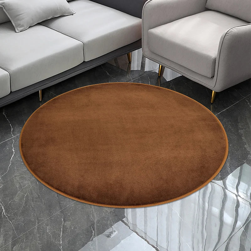 Petit tapis rond texturé marron, posé au sol dans un salon devant un canapé et un fauteuil gris.