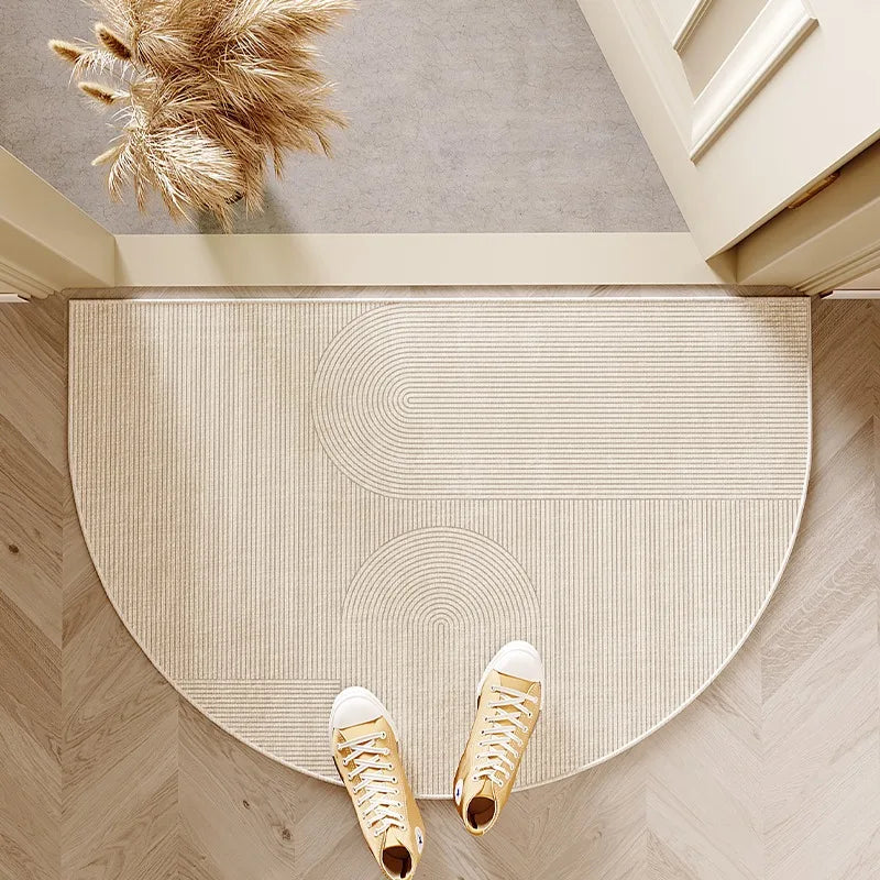Tapis d'entrée en forme de demi-lune à motif d'arches beige, posé devant une porte avec une paire de baskets dessus.