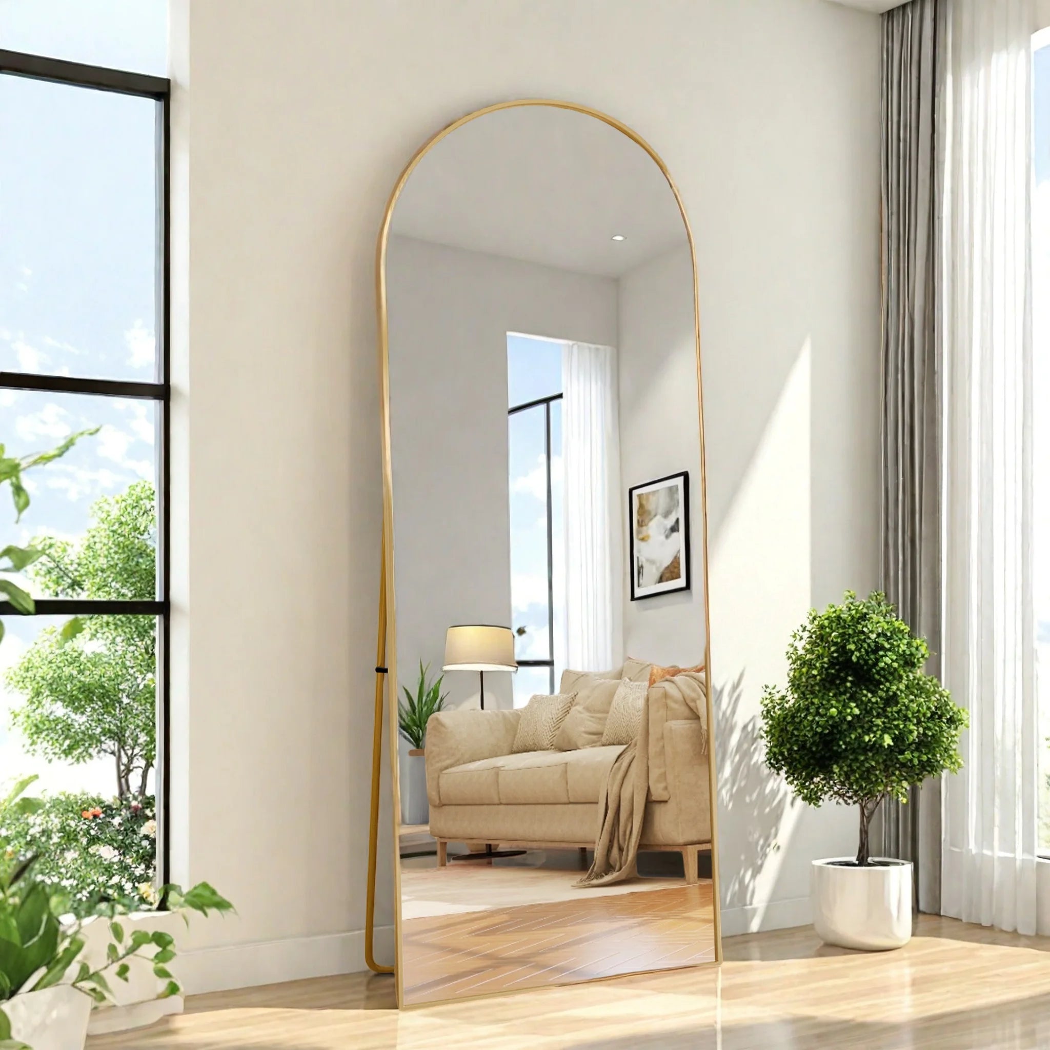 Miroir psyché incurvé Nesty - Cadre doré posé au sol, reflet d'un fauteuil beige et d'une plante verte