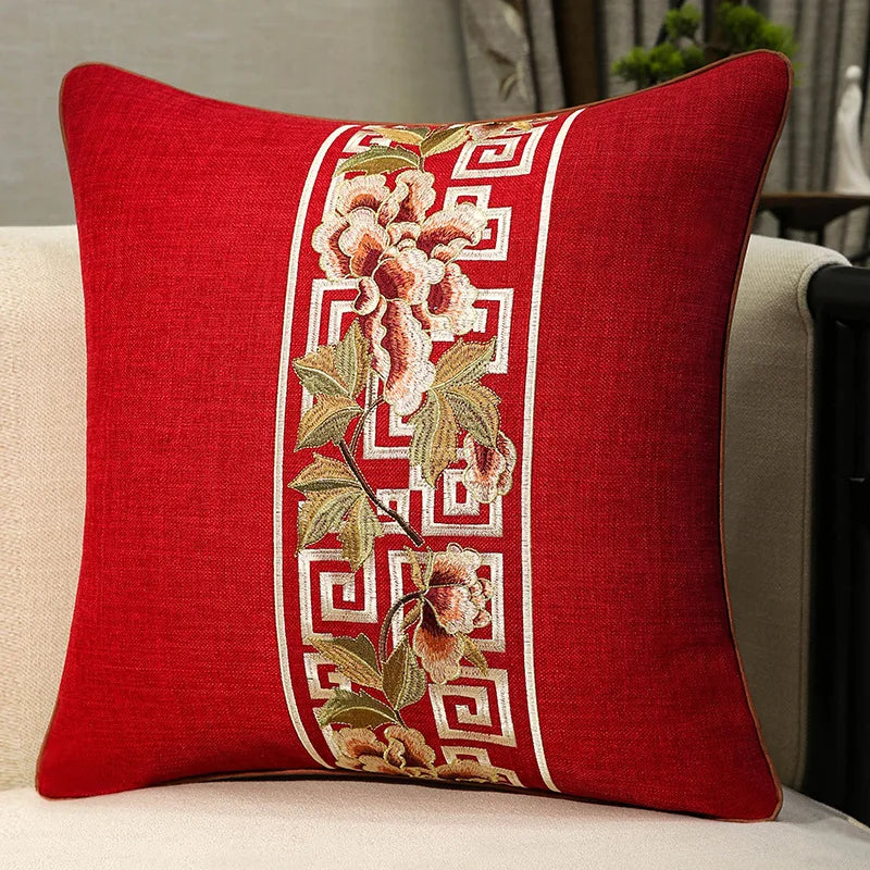 Housse de coussin en coton et lin, broderie florale classique Nesty, housse de coussin rouge avec bande brodée de fleurs roses et motif grec ivoire, posée sur fauteuil