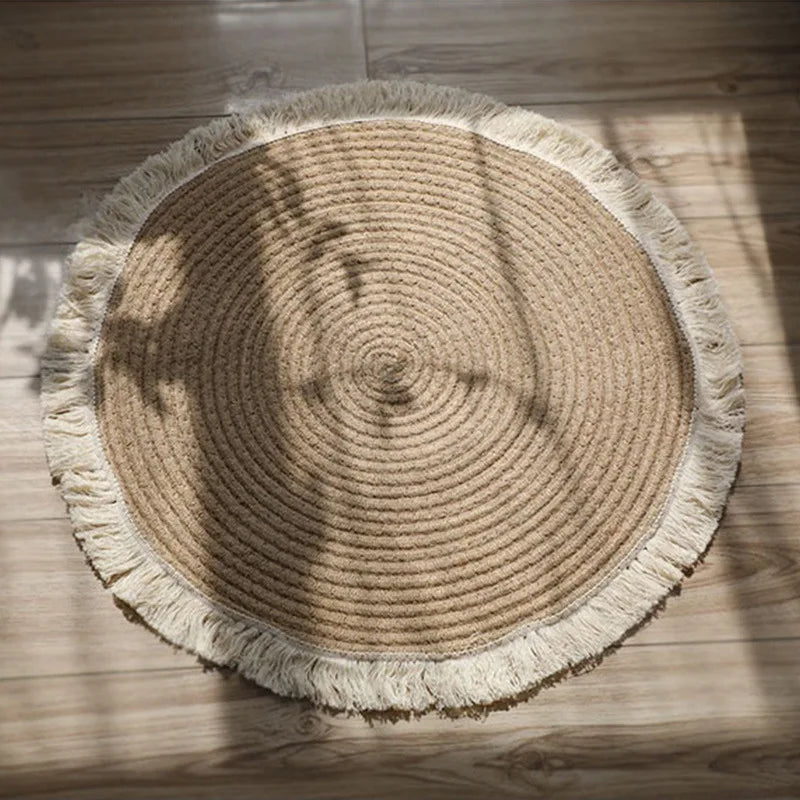 Tapis rond tressé main en jute et rotin à franges, posé au sol en bois, vue du dessus - Nesty