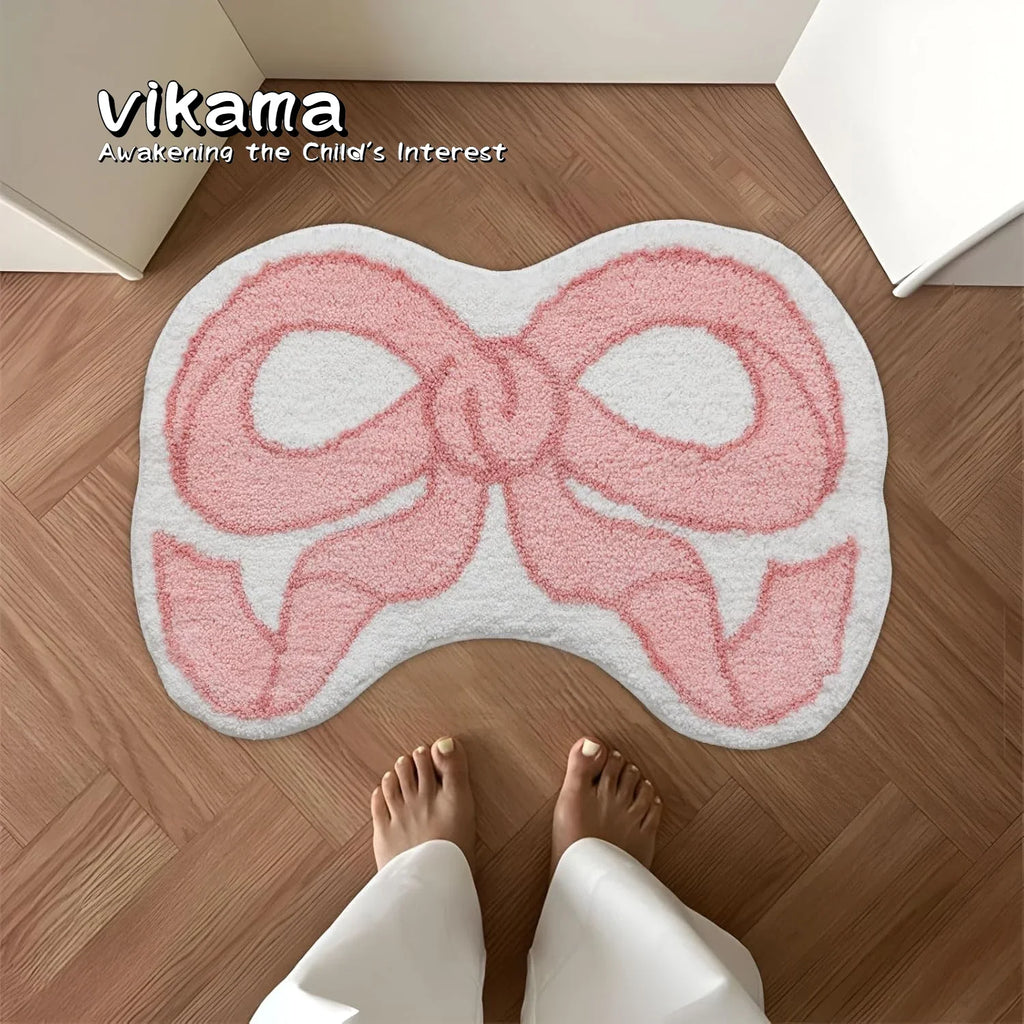 Petit tapis à motif nœud — imitation cachemire - Nesty, tapis en forme de nœud rose et blanc vu de dessus posé sur un parquet, pieds nus à proximité
