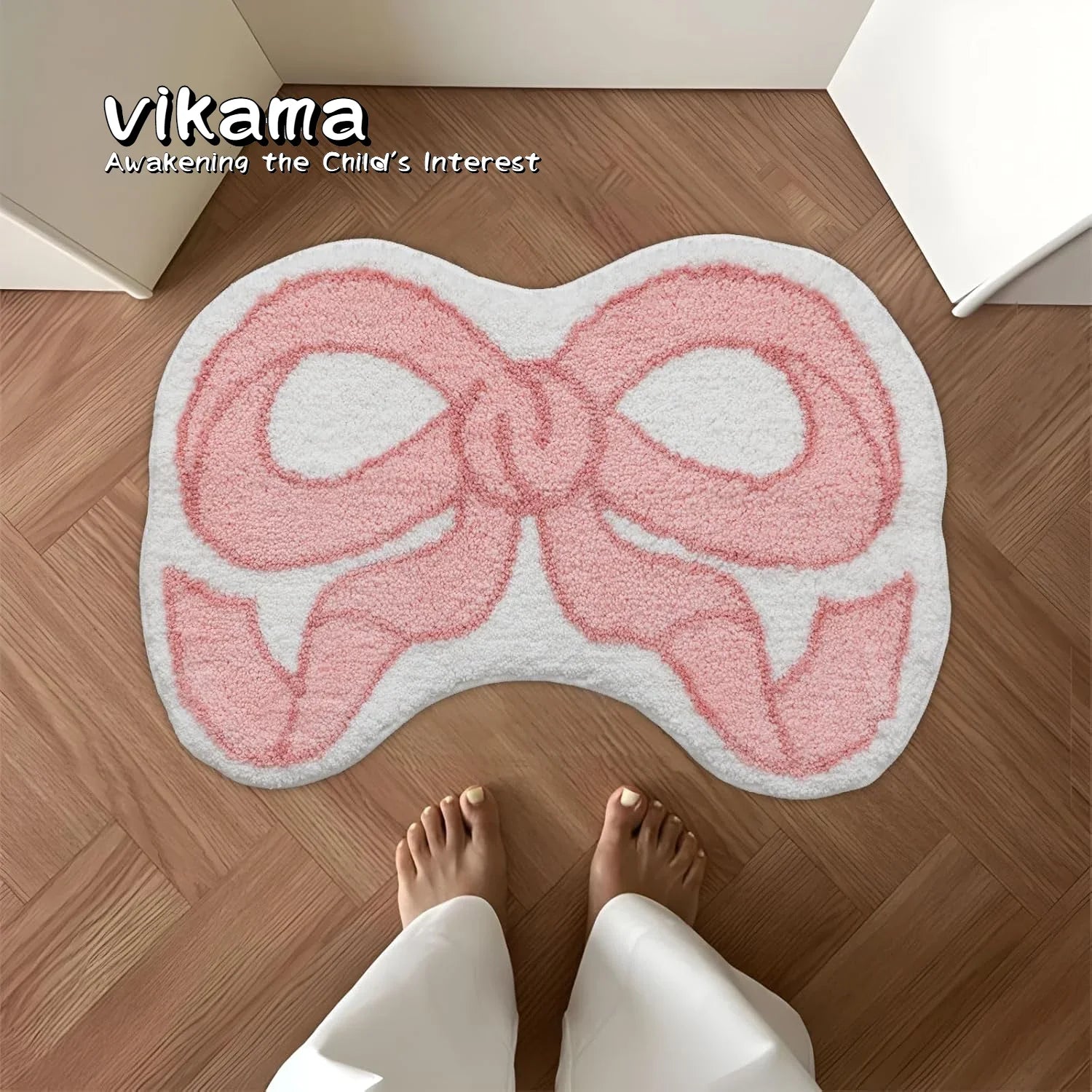 Petit tapis à motif nœud — imitation cachemire - Nesty, tapis en forme de nœud rose et blanc vu de dessus posé sur un parquet, pieds nus à proximité