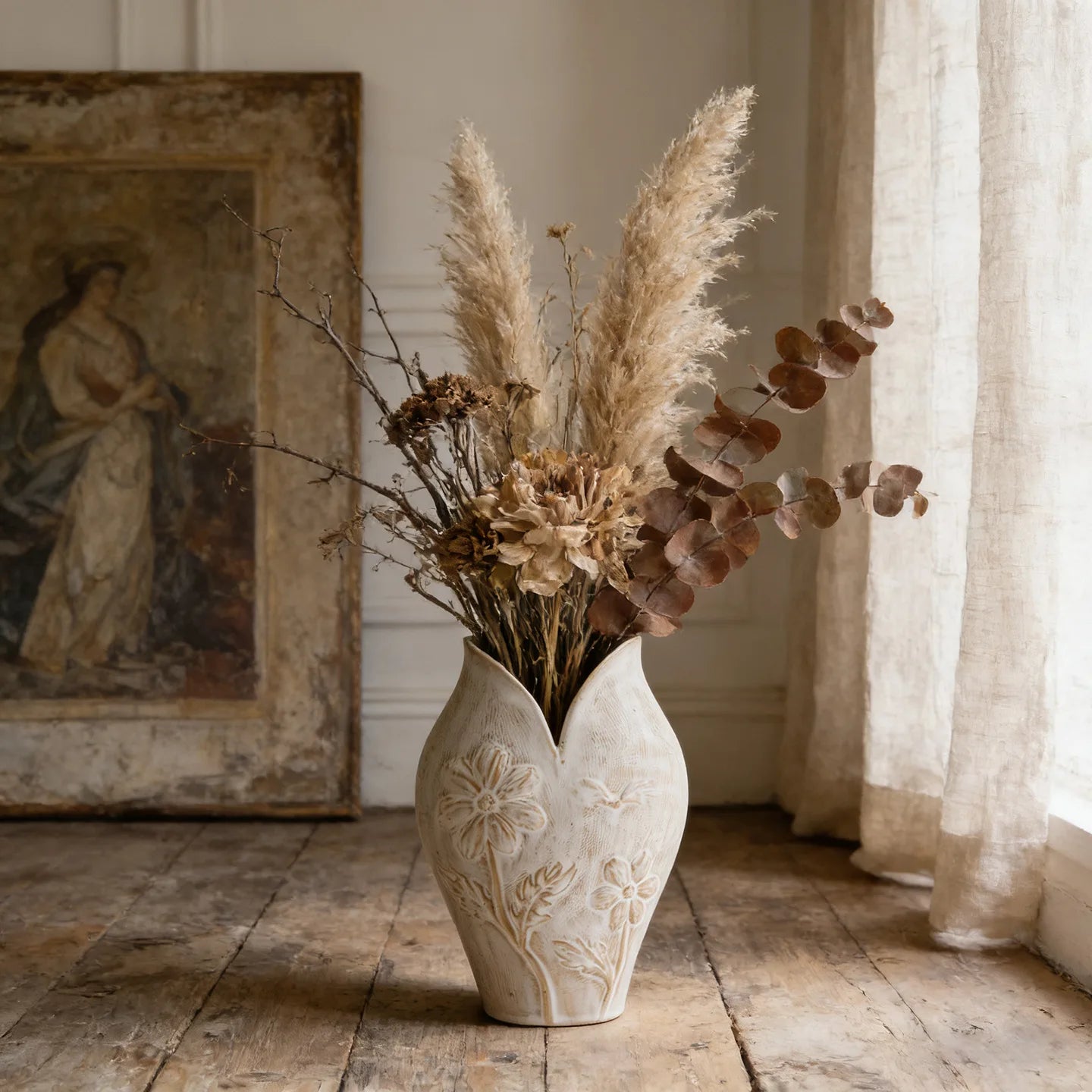 Vase en céramique forme poisson, esprit wabi-sabi Nesty, vase blanc à relief floral, garni de pampa, eucalyptus brun et fleurs séchées, devant un tableau ancien