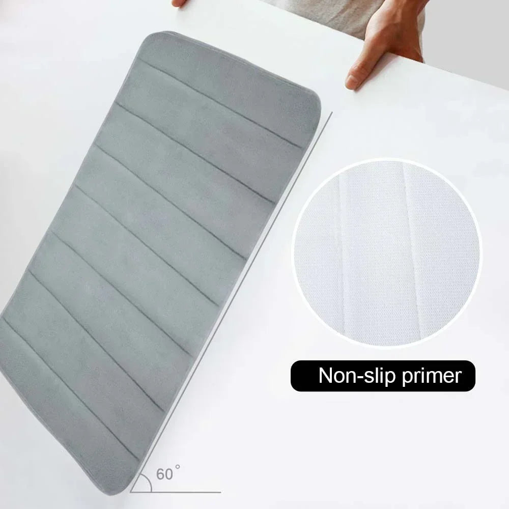 Tapis de bain gris à rainures, présenté à angle de 60° pour montrer sa souplesse, avec un gros plan sur son envers antidérapant.