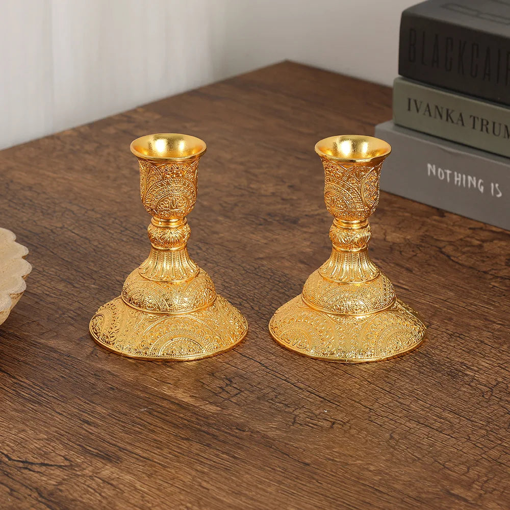 Duo de bougeoirs en métal Nesty - Paire de bougeoirs dorés à motifs ciselés, gros plan sur une table en bois avec des livres