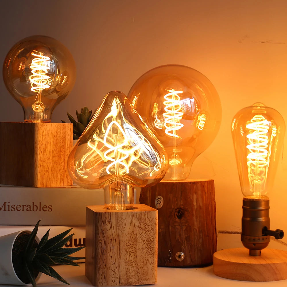Ampoule LED Edison vintage Nesty - Quatre formes allumées, posées sur des socles en bois