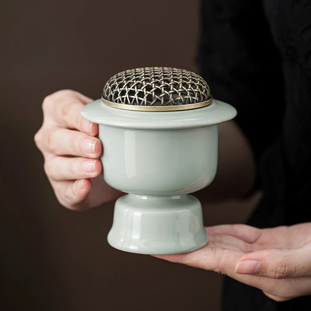 Brûle-parfum électrique en céramique Nesty - Modèle vert celadon tenu à deux mains