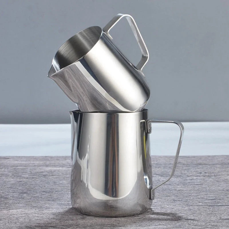 Pichet à lait en inox pour mousse et latte art Nesty, deux pichets posés l'un contre l'autre en angle, sur fond gris