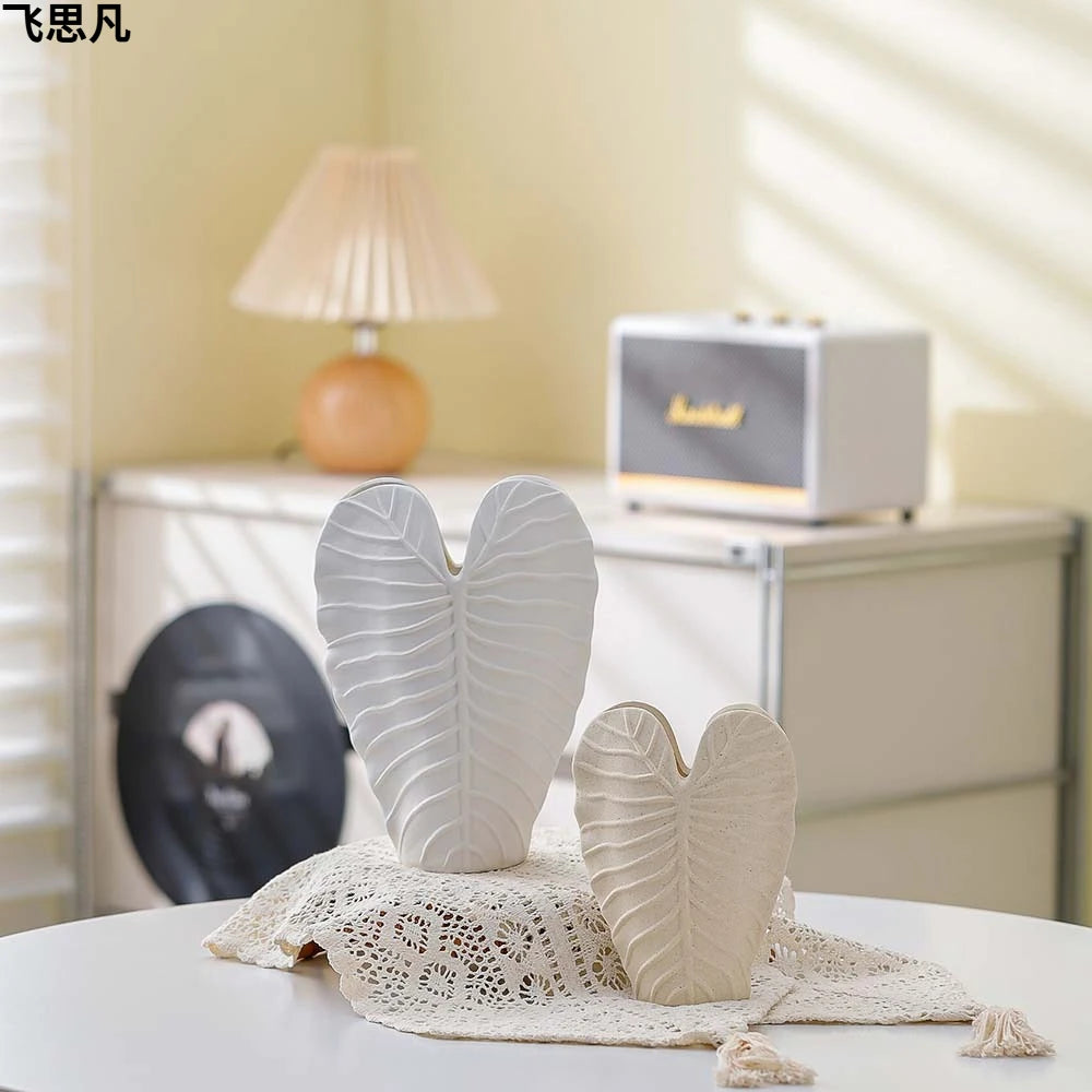 Vase en porcelaine texturé feuille cœur, finition mate Nesty, deux tailles en forme de feuille en coeur, blanc et beige, posées sur un torchon en dentelle