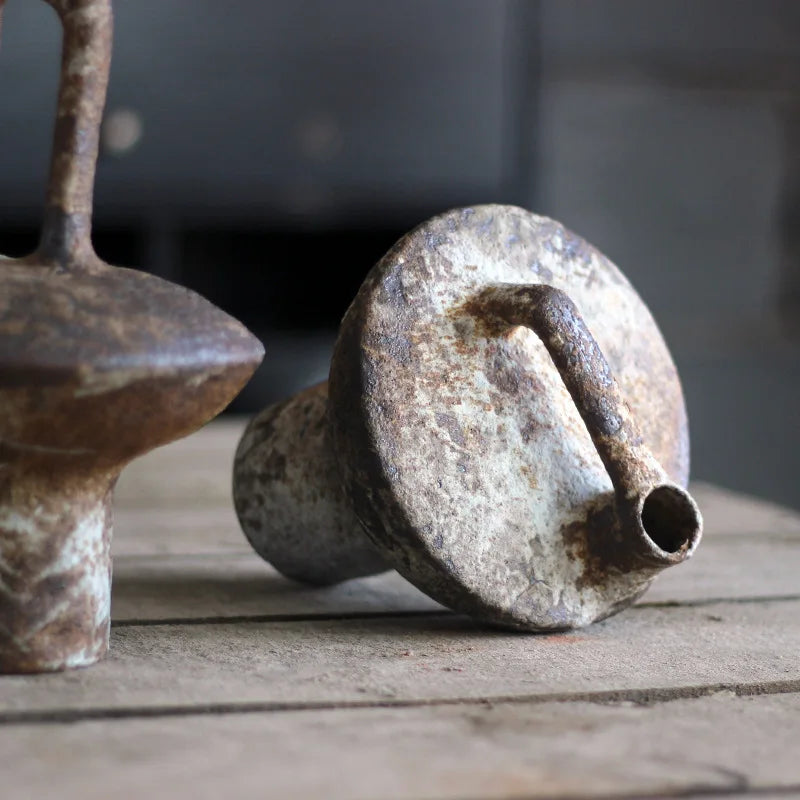 Vase en terre cuite, esprit rétro et brut Nesty, gros plan sur l'embouchure et l'anse de deux vases terre cuite brute effet rouille, posés sur planches en bois