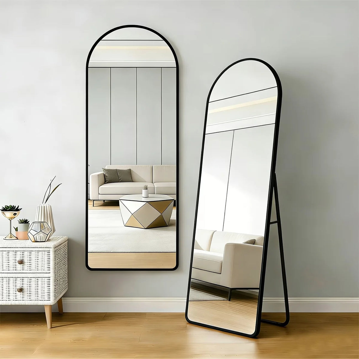 Miroir grand format Nesty - Cintré ou rond, cadre aluminium, deux formats de présentation côte à côte, miroir rectangulaire cintré mural et miroir cintré sur pied appuyé, cadre noir, dans un intérieur beige avec commode en rotin
