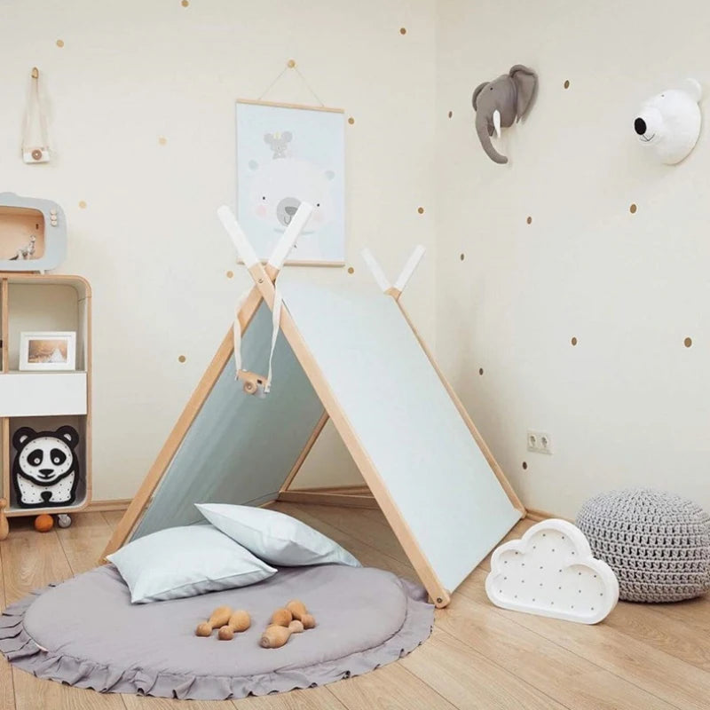 Tapis rond en coton pour bébé — coin jeux - Nesty, variante grise à bordure volantée installée sous une tente tipi dans une chambre d'enfant