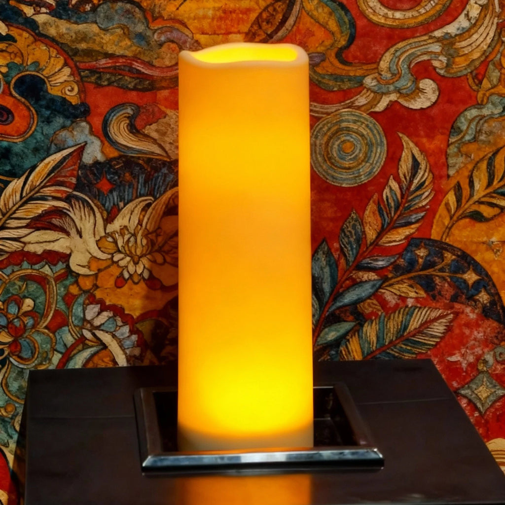 Bougies LED pilier vacillantes, télécommande, intérieur et extérieur Nesty, bougie LED pilier haute et fine, lumière ambrée vive, posée sur coffret noir devant tapisserie colorée