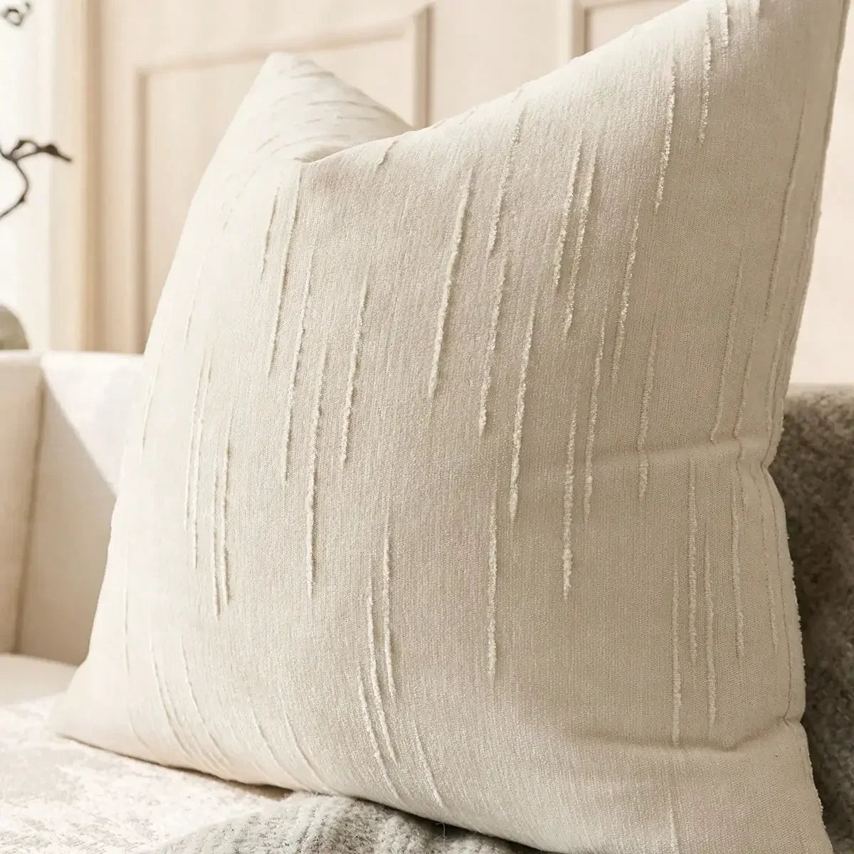 Housse de coussin en lin imitation, beige, motif géométrique bohème Nesty, gros plan sur la texture beige à fines rayures verticales brossées d'une housse de coussin carrée, posée sur canapé