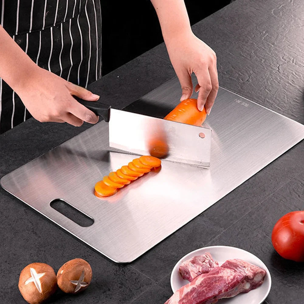 Planche à pâtisserie en acier inoxydable 316, format rectangulaire Nesty, mains découpant une carotte en rondelles sur la planche, tomate et champignons à proximité
