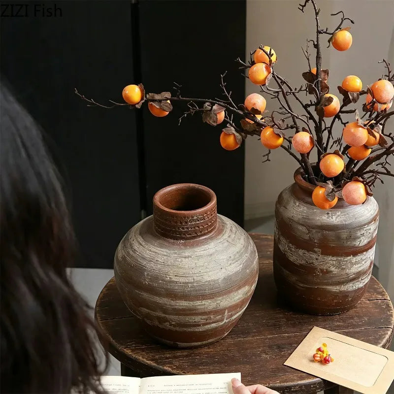Vase en céramique strié, esprit wabi-sabi rétro Nesty, deux tailles garnies de branches à fruits orange, sur table en bois avec personne lisant