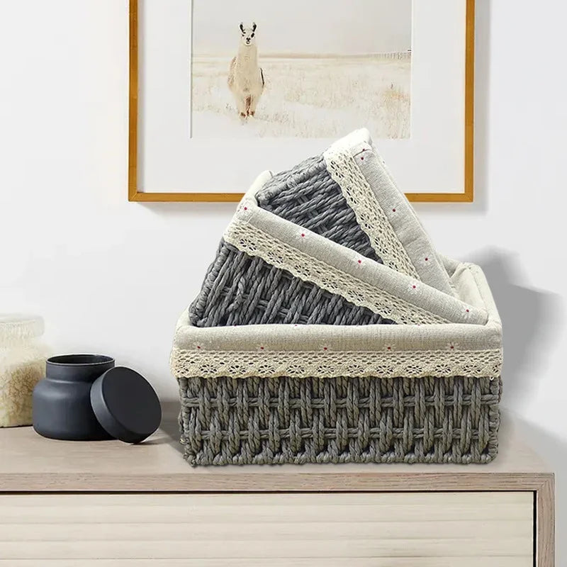 Panier de rangement tressé à doublure fleurie Nesty - Version grise empilée, sur meuble sous un tableau de lama